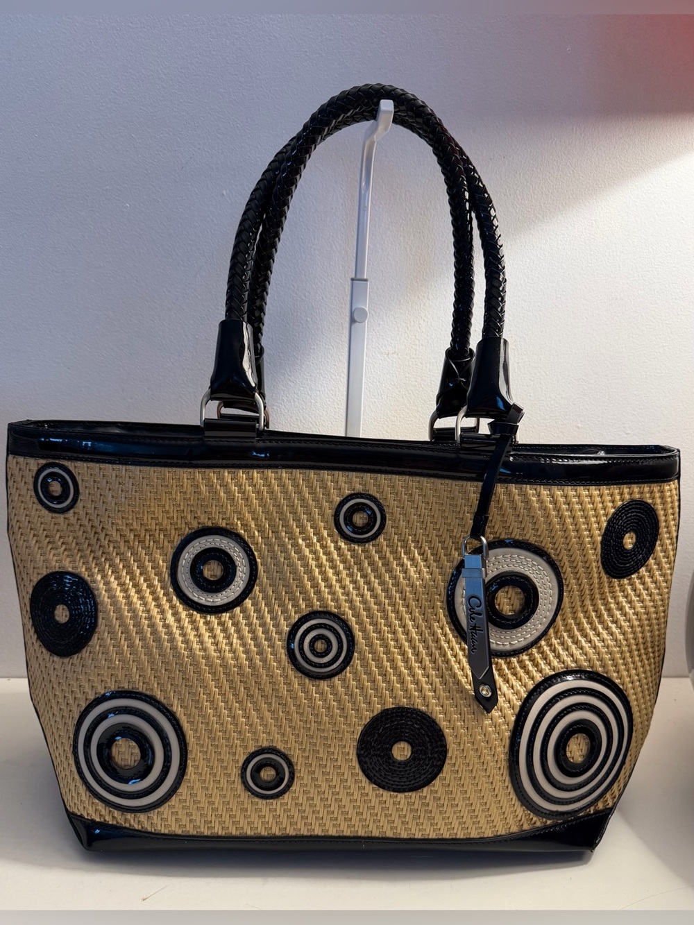 Cole Haan natural straw bag accented with black patent & circle appliqués.